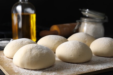 Photo of Raw dough balls with flour on table