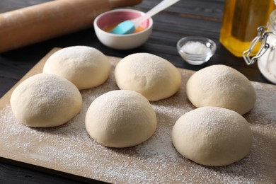 Raw dough balls, yolk, salt and rolling pin on black wooden table