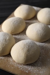 Photo of Raw dough balls with flour on table, closeup