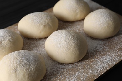 Raw dough balls with flour on table, closeup