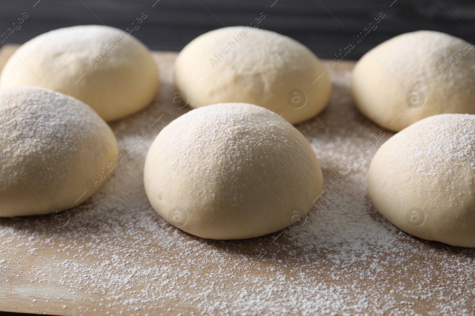 Photo of Raw dough balls with flour on table, closeup