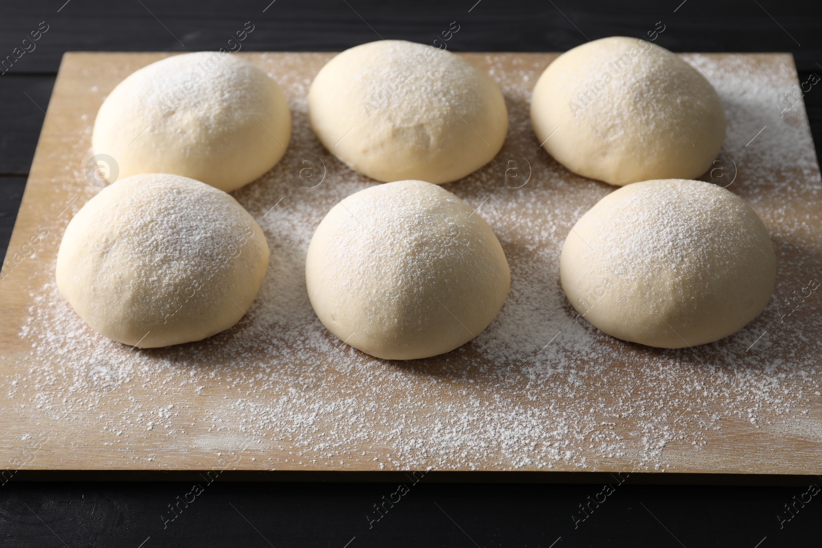 Photo of Raw dough balls on black wooden table