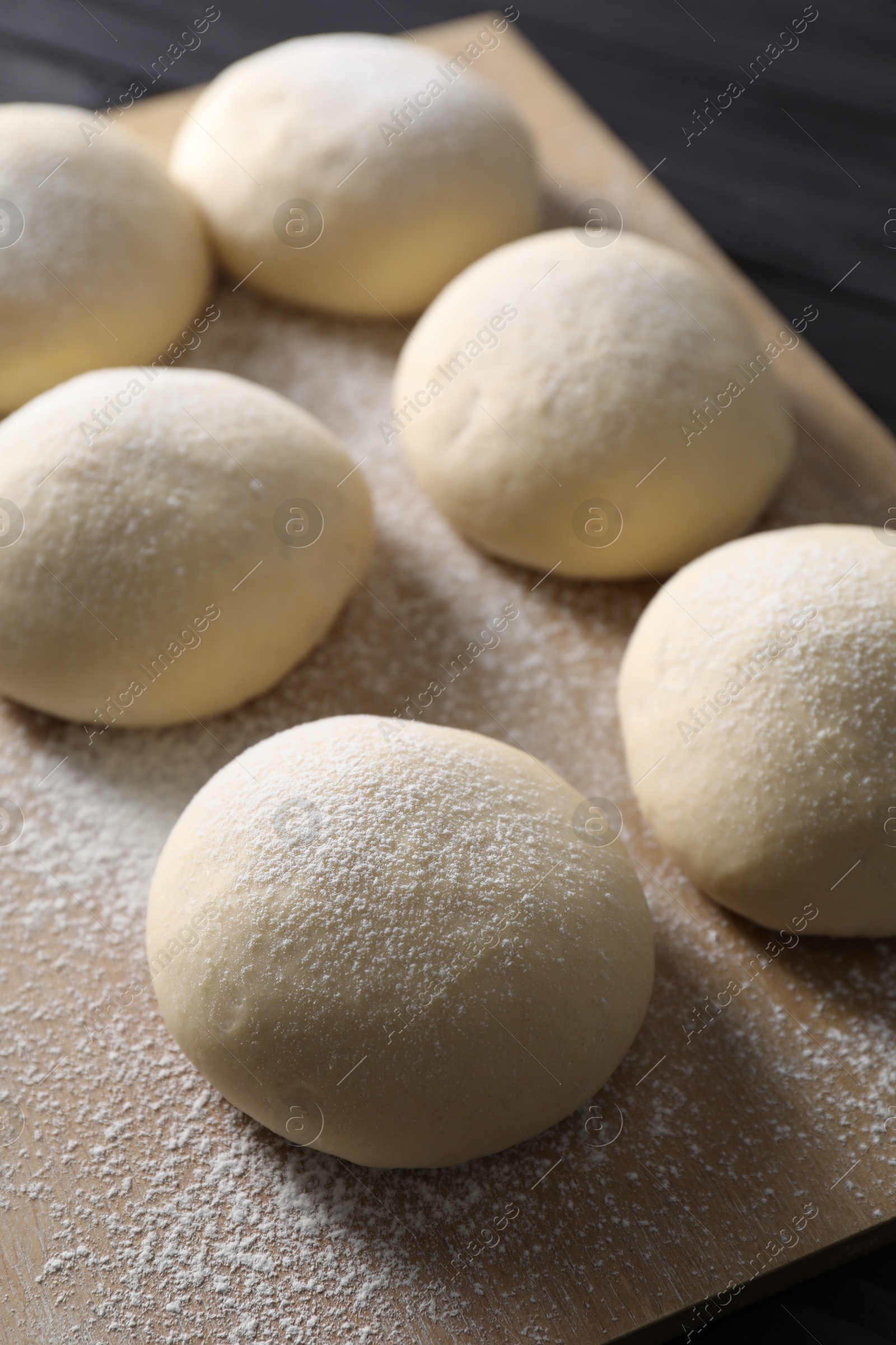 Photo of Raw dough balls with flour on table, closeup