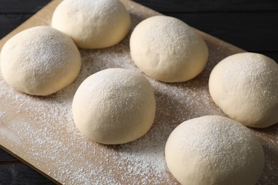 Photo of Raw dough balls on black wooden table