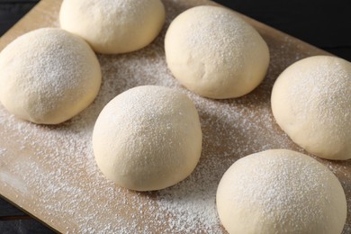 Photo of Raw dough balls with flour on table, closeup