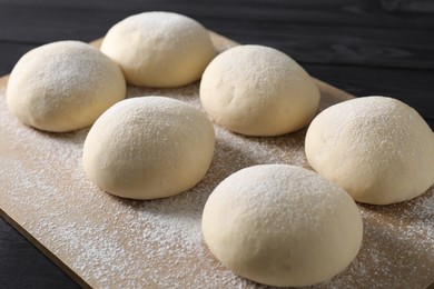 Photo of Raw dough balls on black wooden table, closeup