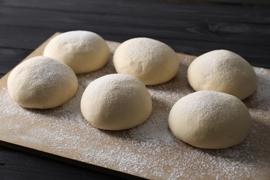 Photo of Raw dough balls on black wooden table