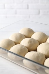 Photo of Raw dough balls in baking dish on white wooden table