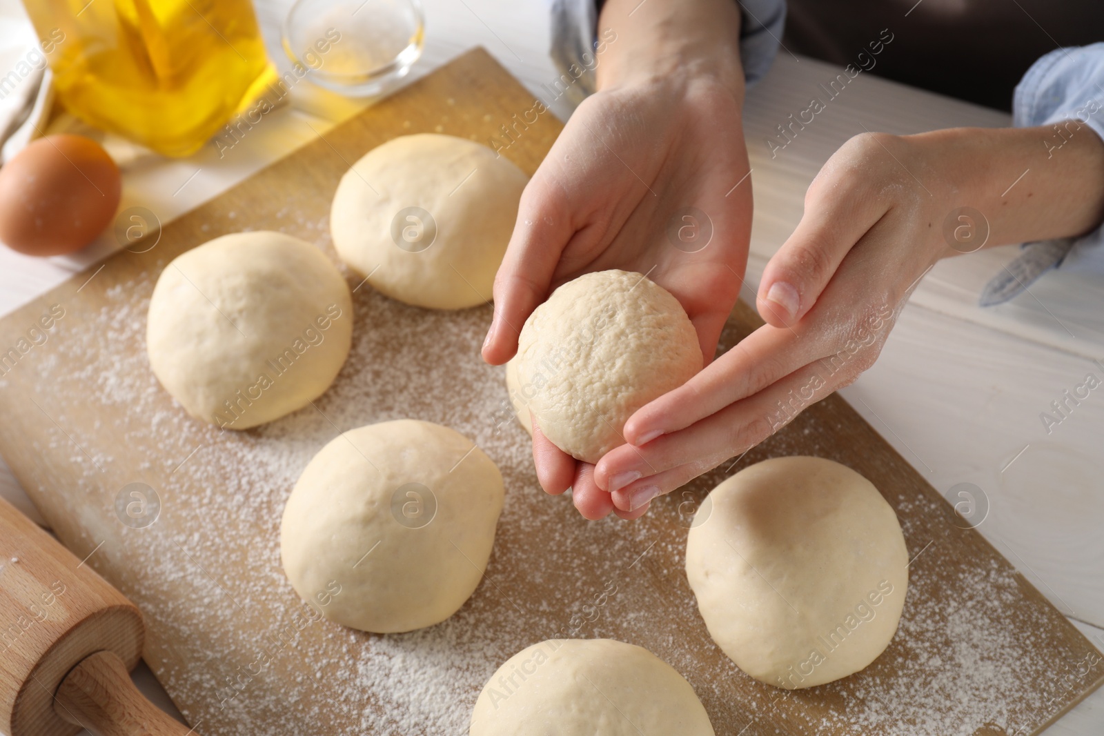 Photo of Woman making dough ball at white wooden table, closeup