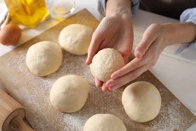 Woman making dough ball at white wooden table, closeup