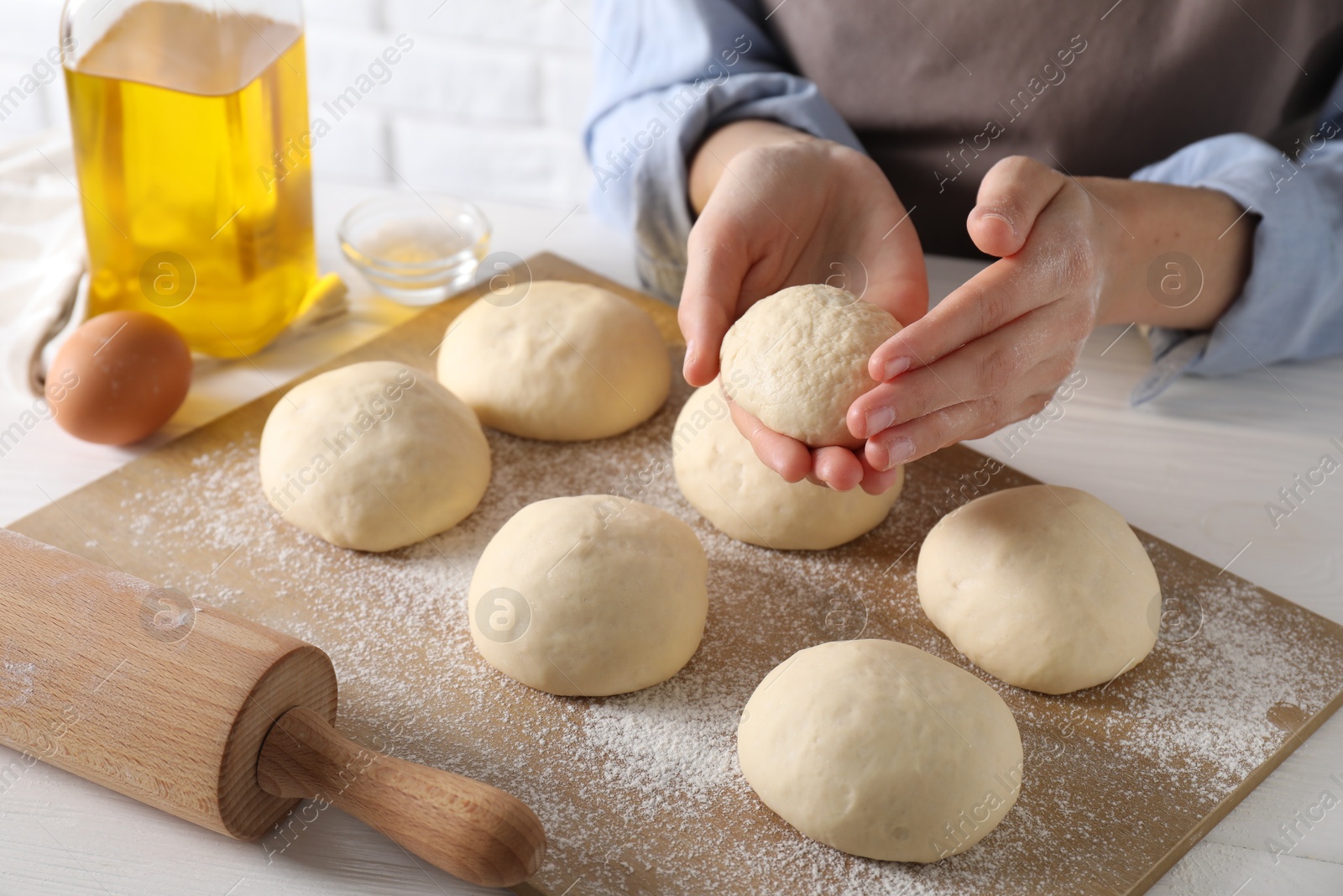 Photo of Woman making dough ball at white wooden table, closeup