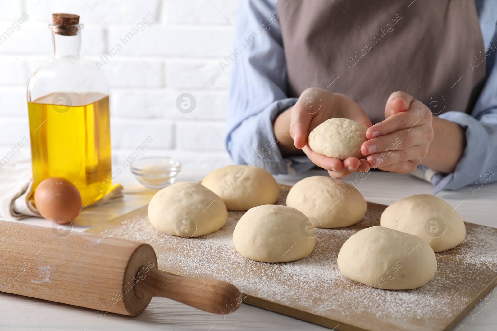 Photo of Woman making dough ball at white wooden table, closeup