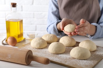 Woman making dough ball at white wooden table, closeup