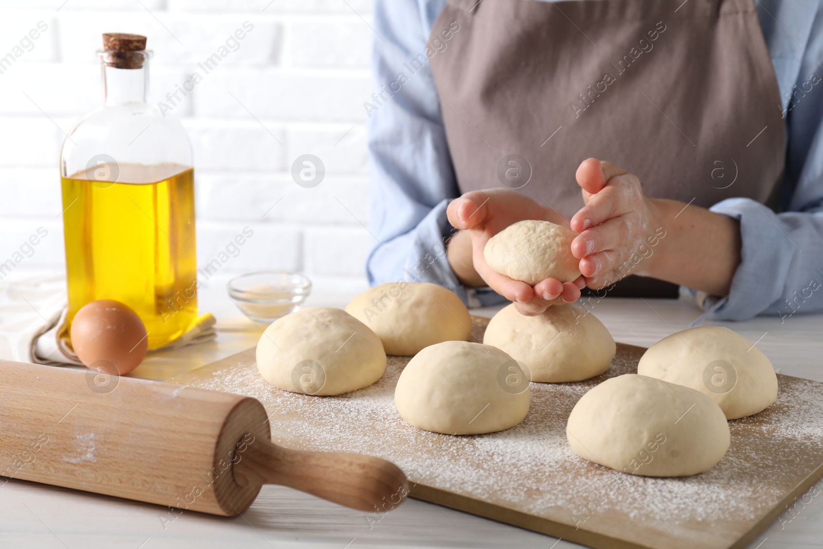 Photo of Woman making dough ball at white wooden table, closeup