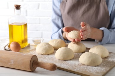 Woman making dough ball at white wooden table, closeup