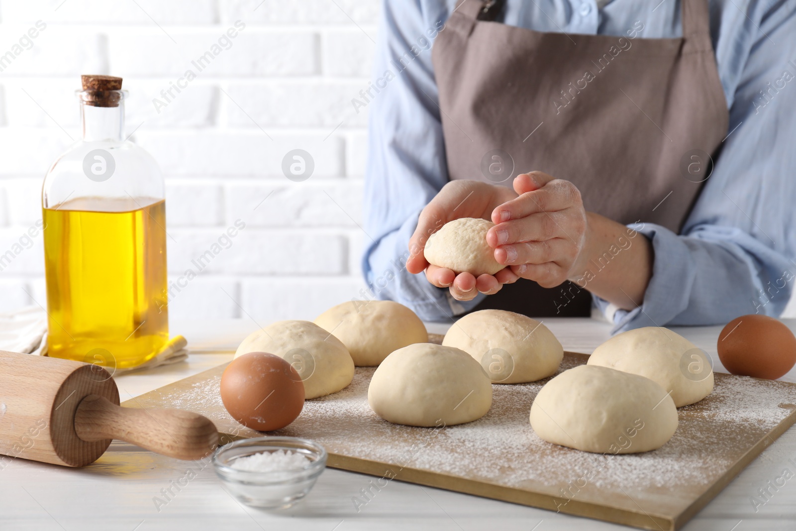 Photo of Woman making dough ball at white wooden table, closeup