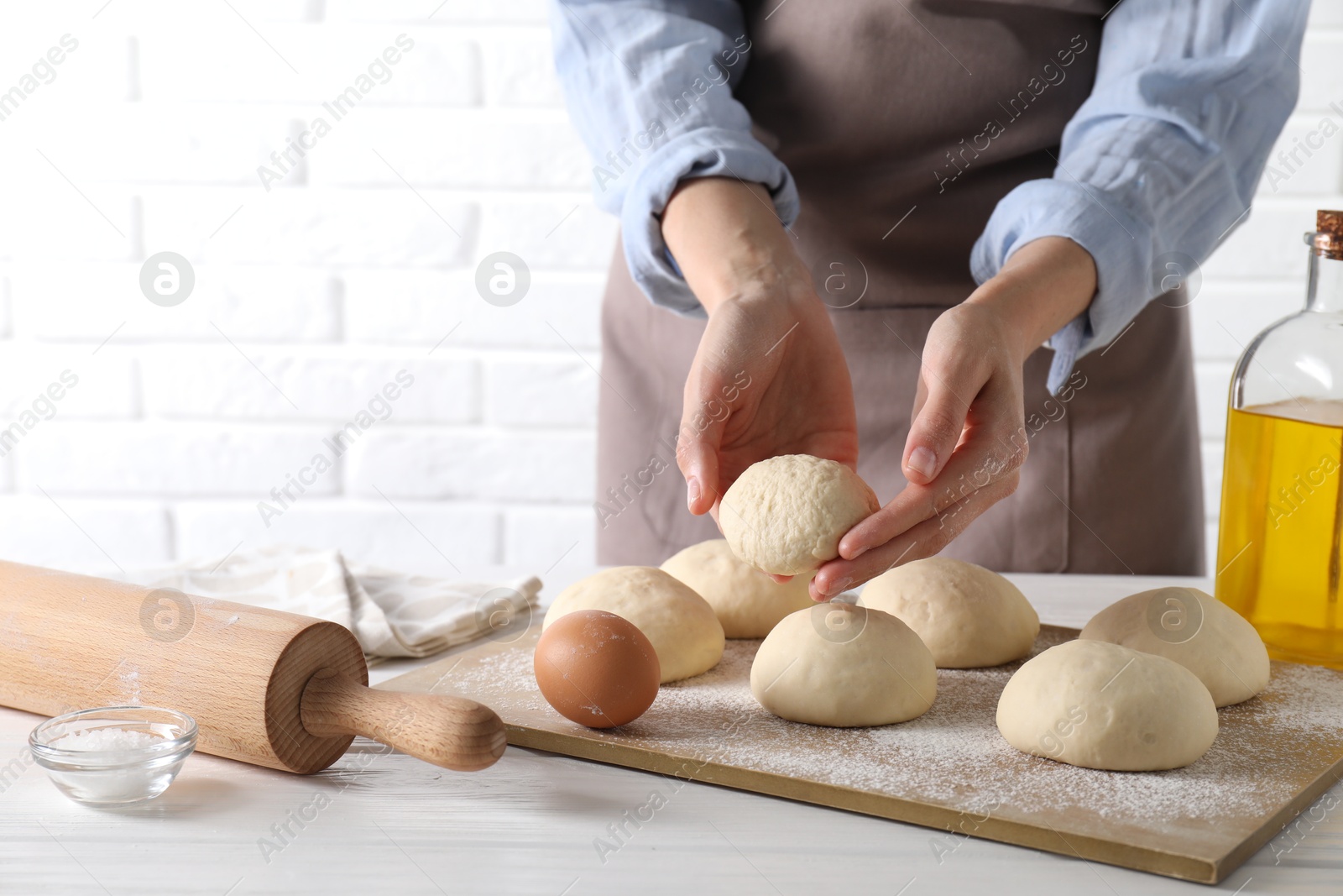 Photo of Woman making dough ball at white wooden table, closeup