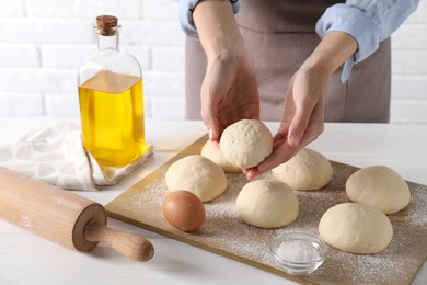 Woman making dough ball at white wooden table, closeup