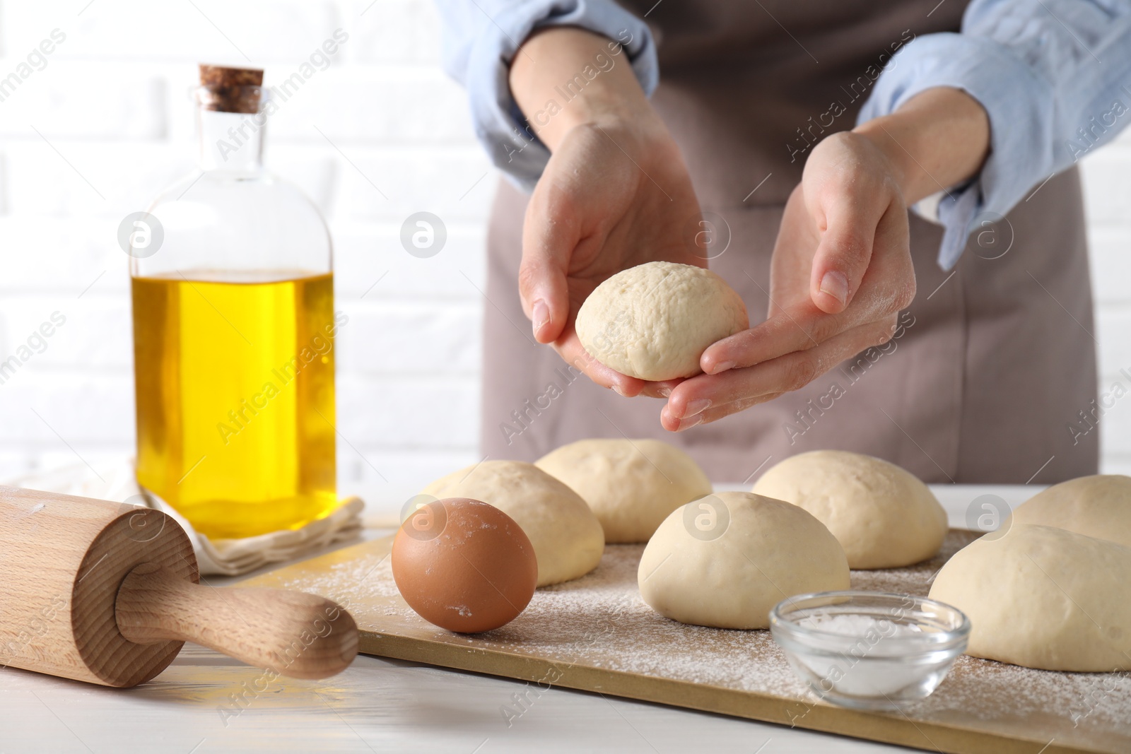 Photo of Woman making dough ball at white wooden table, closeup