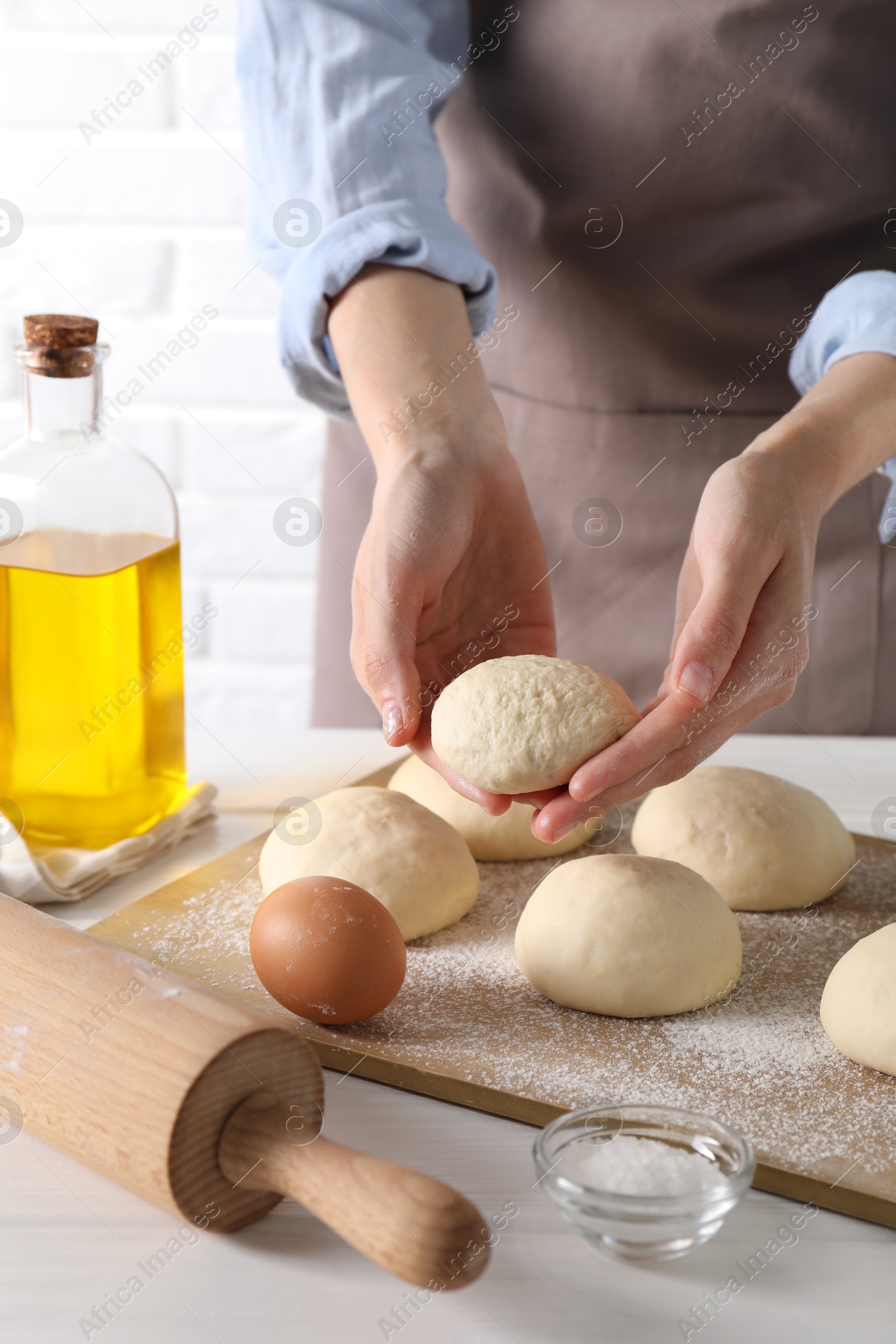 Photo of Woman making dough ball at white wooden table, closeup