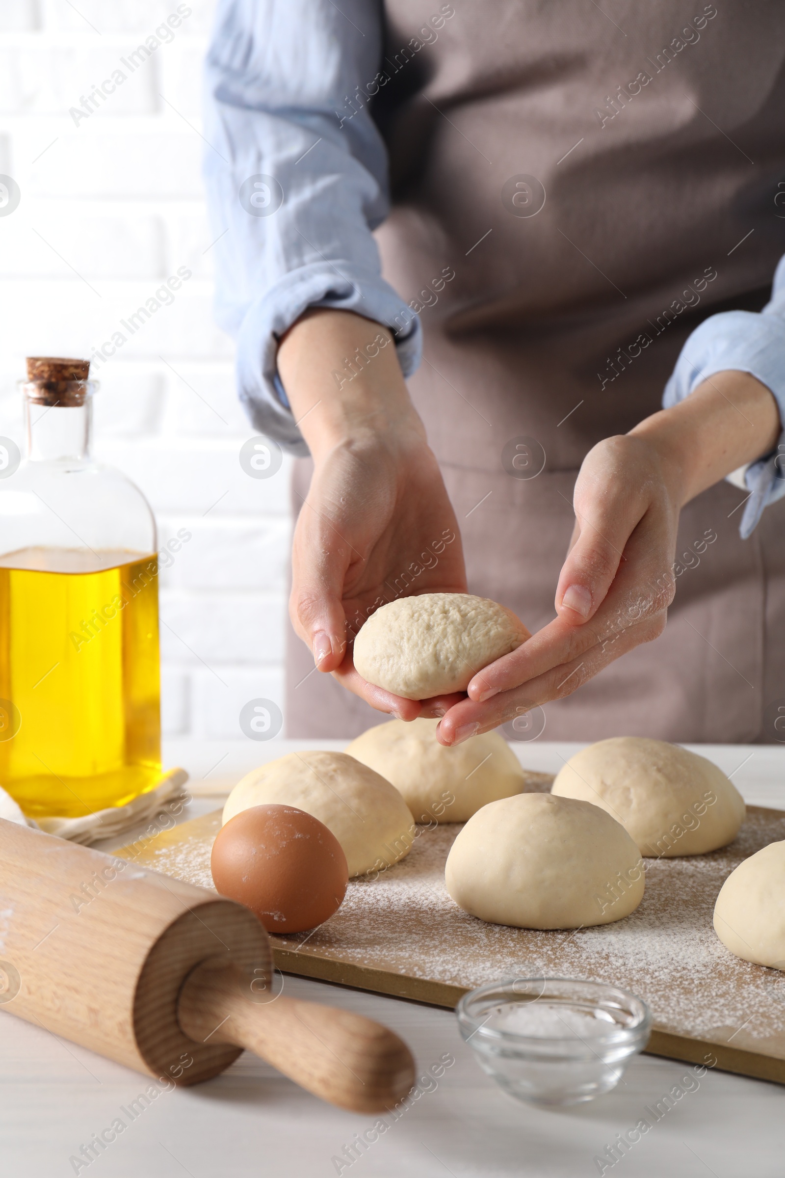 Photo of Woman making dough ball at white wooden table, closeup