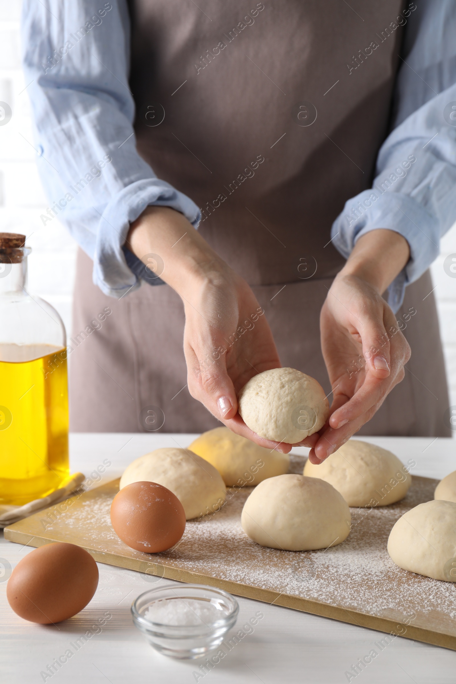 Photo of Woman making dough ball at white wooden table, closeup