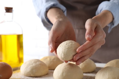 Photo of Woman making dough ball at table, closeup