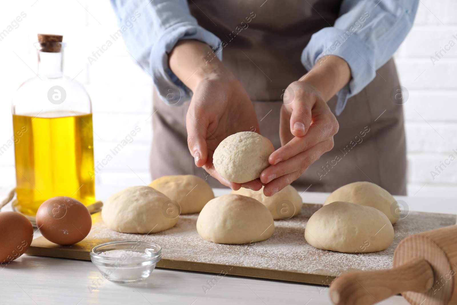 Photo of Woman making dough ball at white wooden table, closeup