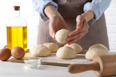 Woman making dough ball at white wooden table, closeup