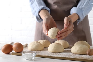 Photo of Woman making dough ball at white wooden table, closeup