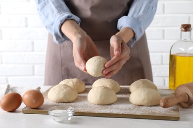 Photo of Woman making dough ball at white wooden table, closeup