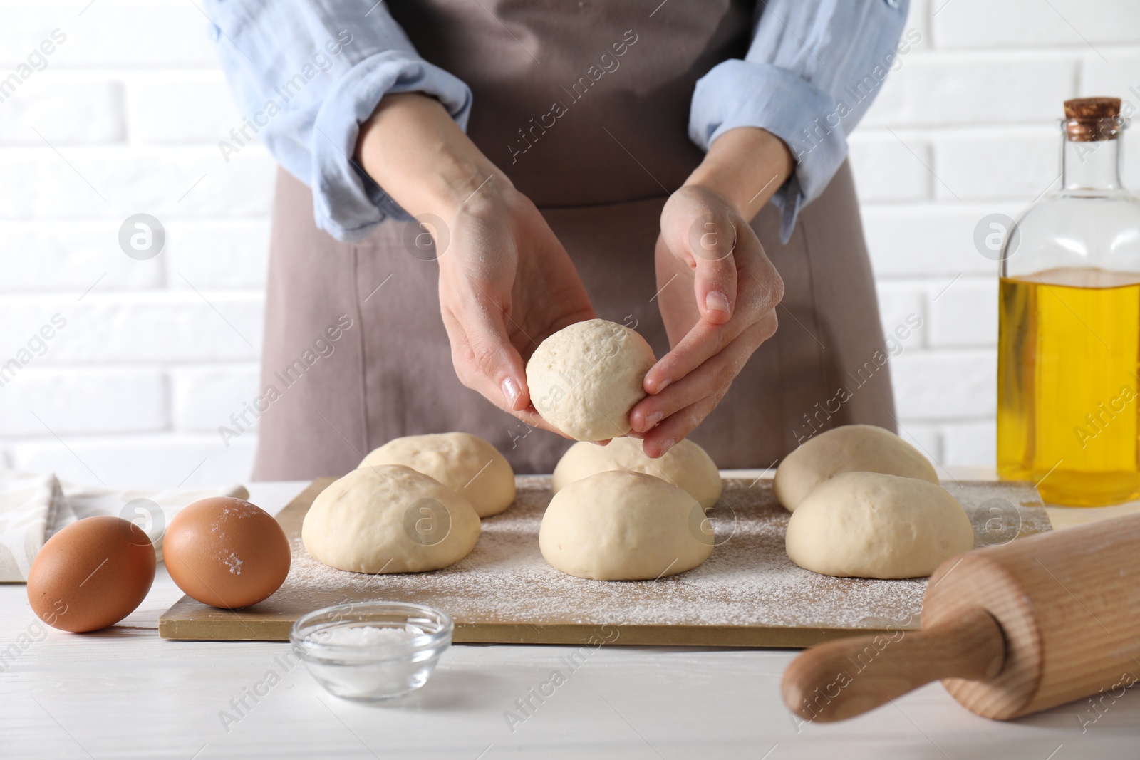 Photo of Woman making dough ball at white wooden table, closeup