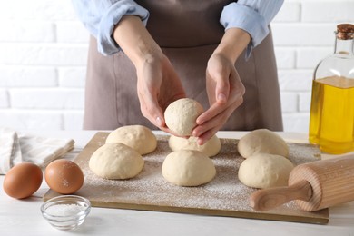 Woman making dough ball at white wooden table, closeup