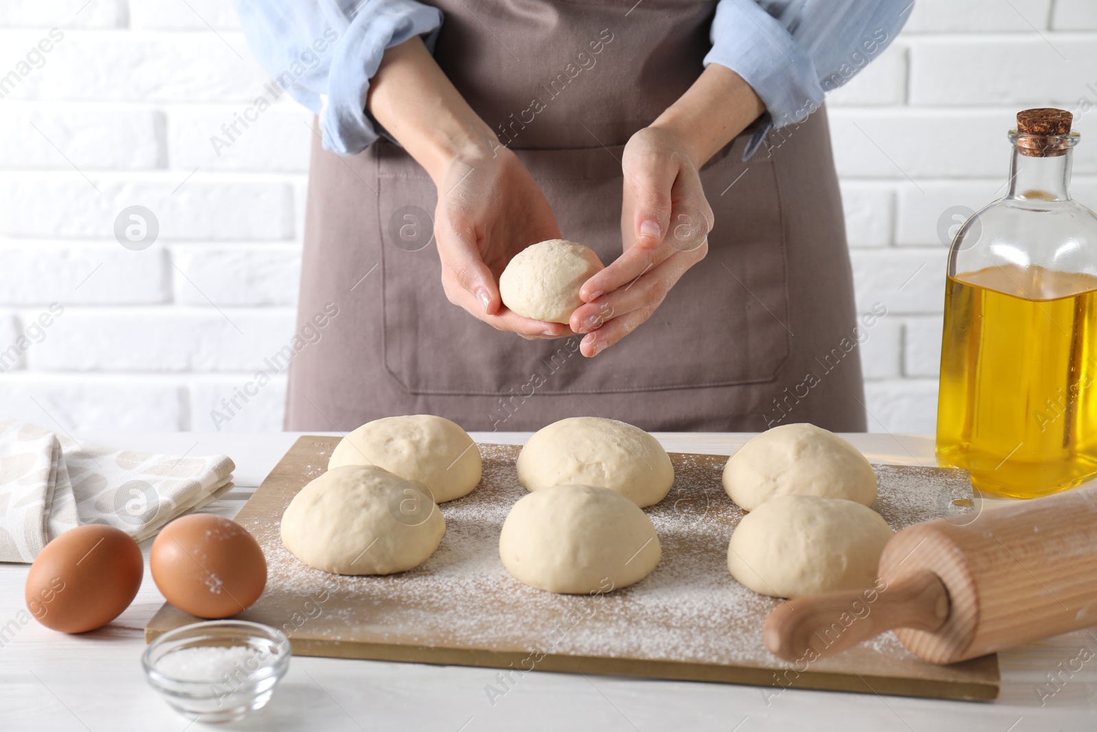 Photo of Woman making dough ball at white wooden table, closeup