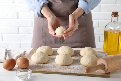 Woman making dough ball at white wooden table, closeup