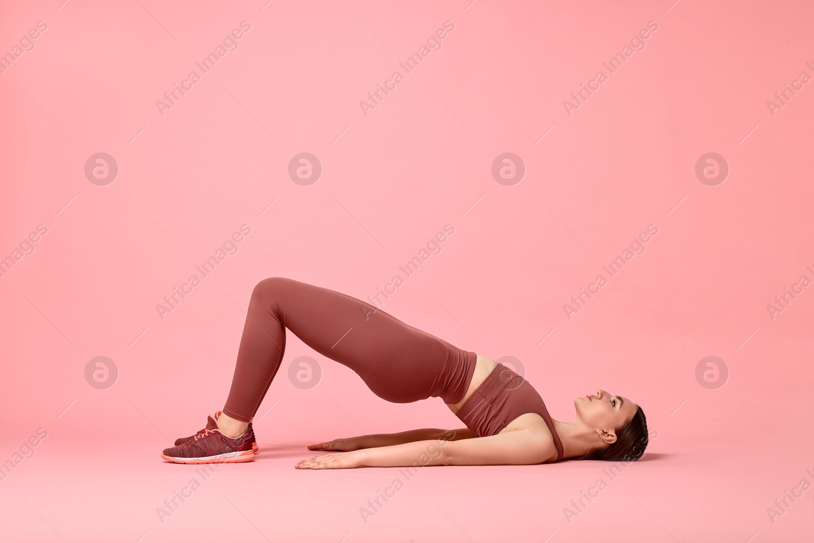 Photo of Young woman doing aerobic exercise on pink background