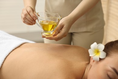 Photo of Aromatherapy. Woman receiving back massage with oil in spa salon, closeup