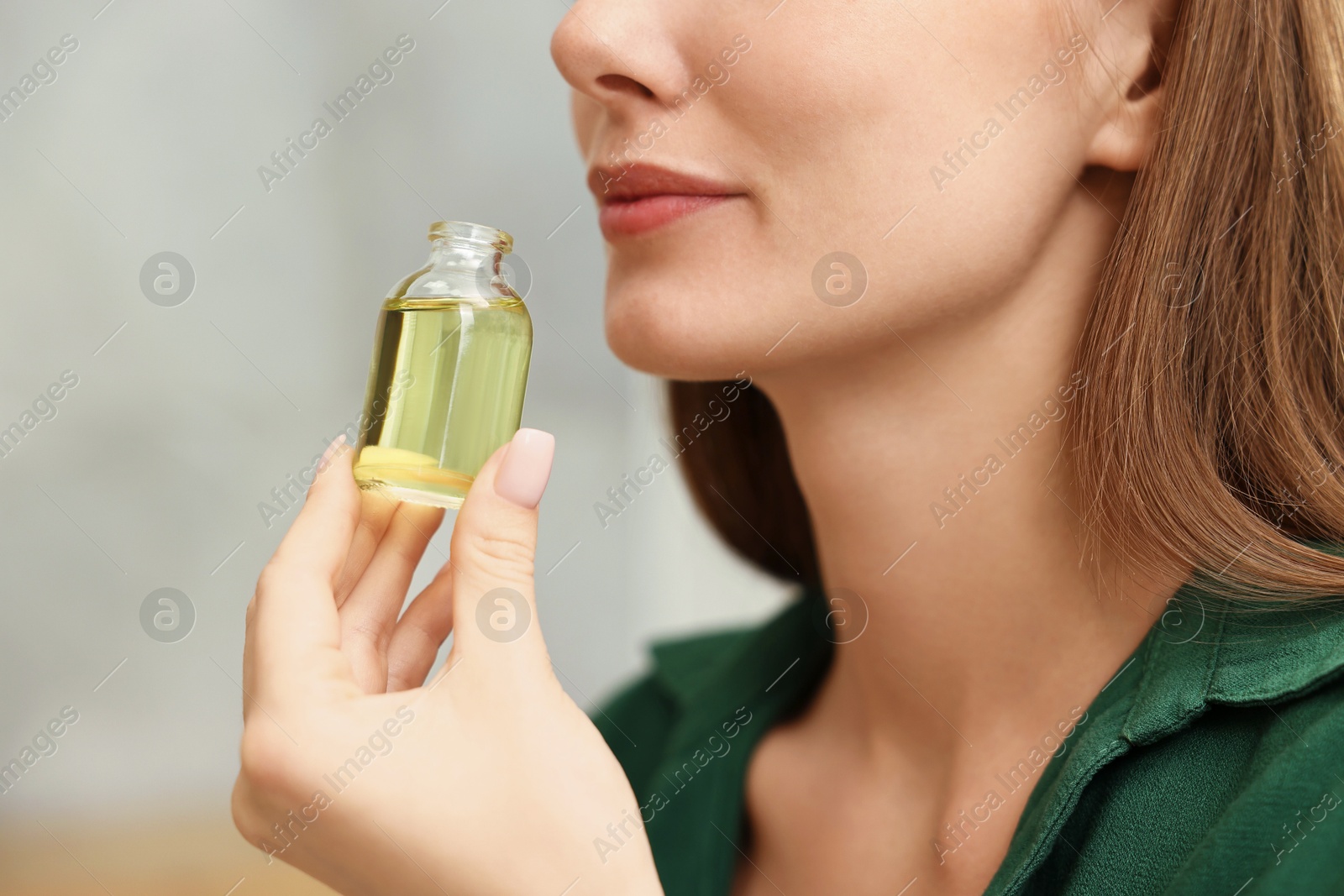 Photo of Aromatherapy. Woman with bottle of essential oil on light background, closeup