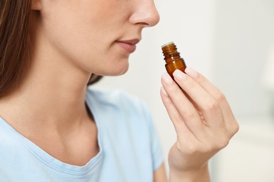 Photo of Aromatherapy. Woman with bottle of essential oil on light background, closeup