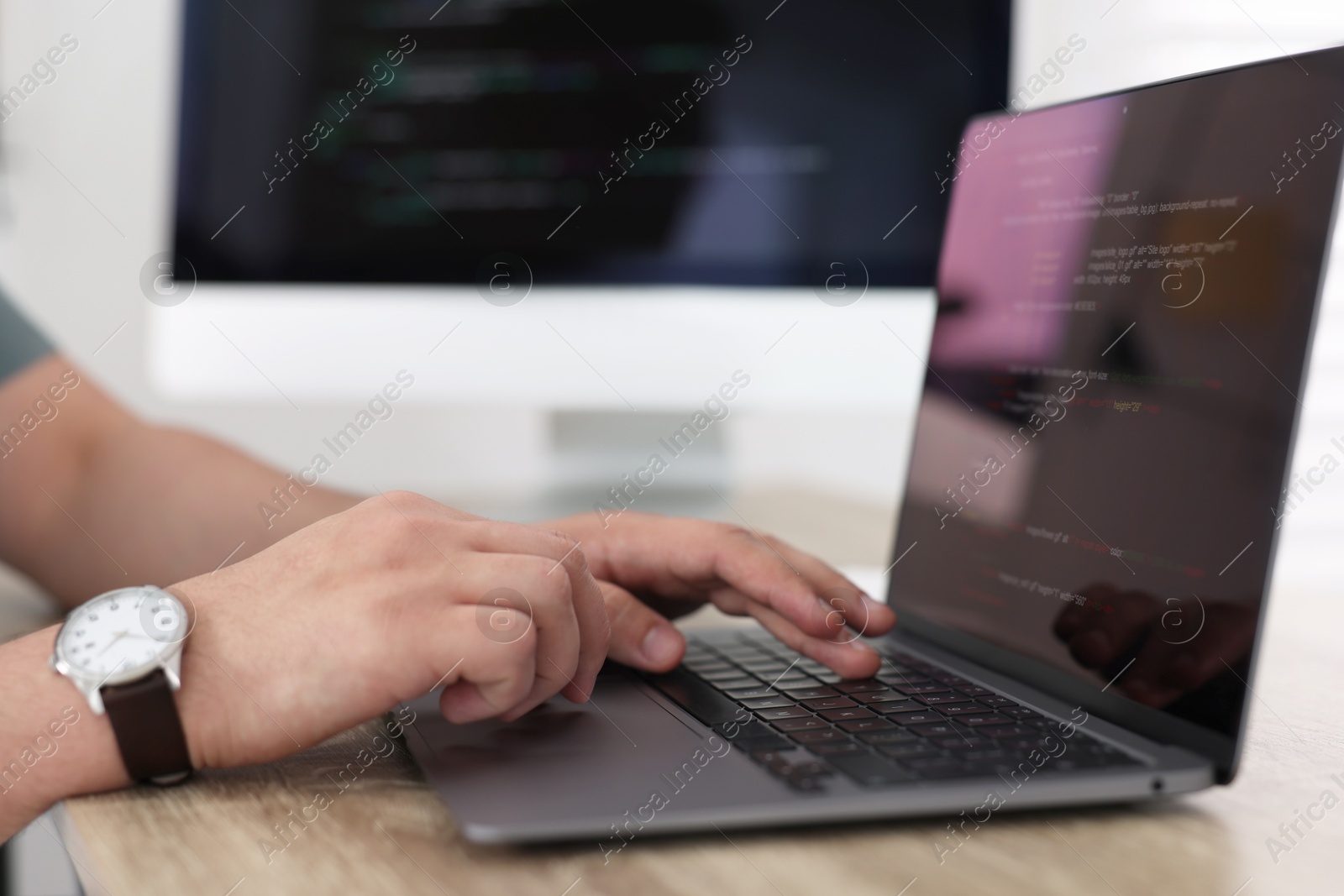 Photo of Programmer working with laptop at desk in office, closeup