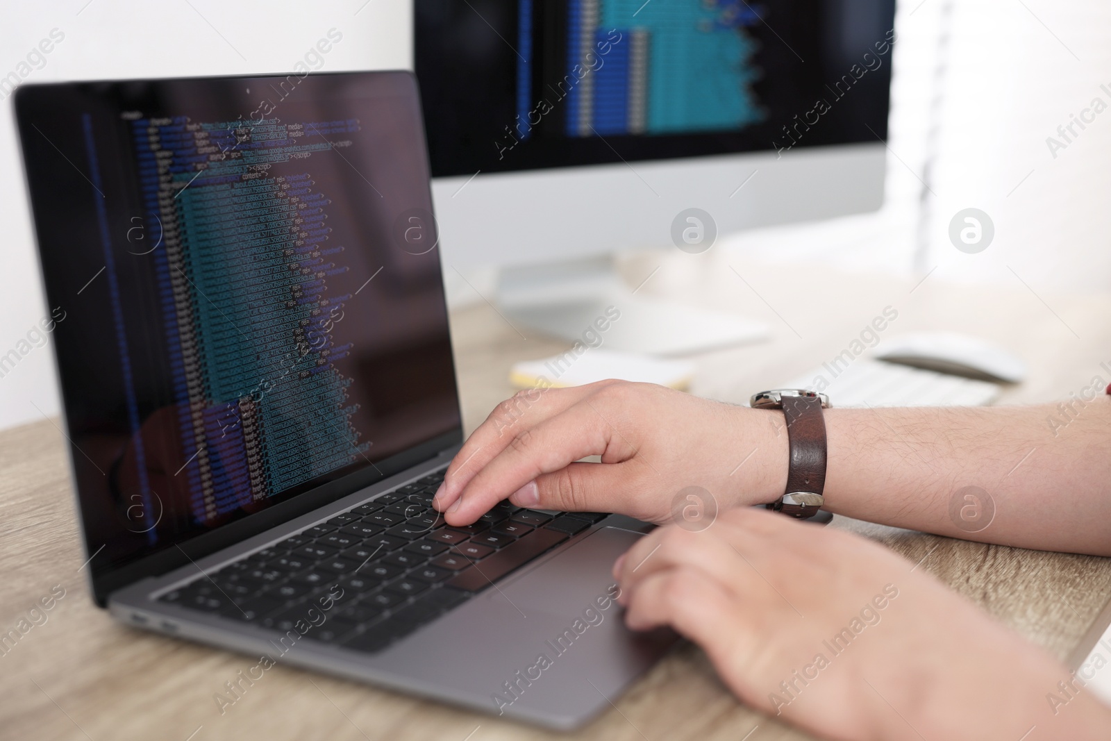 Photo of Programmer working with laptop at desk in office, closeup