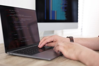 Photo of Programmer working with laptop at desk in office, closeup