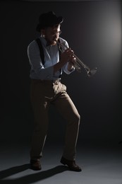 Professional musician playing trumpet on dark background