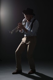 Professional musician playing trumpet on dark background