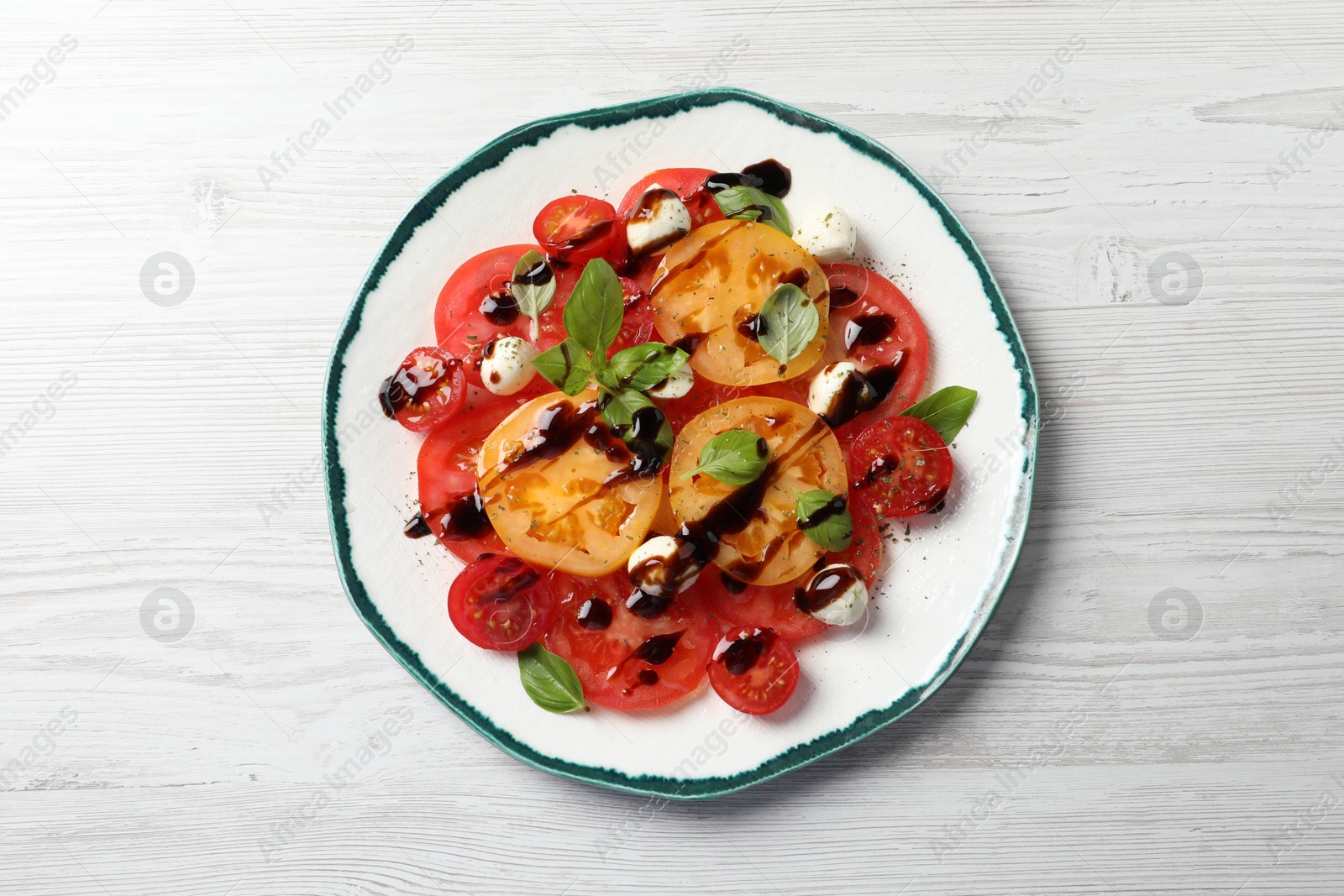 Photo of Tasty salad with balsamic vinegar and mozzarella on white wooden table, top view