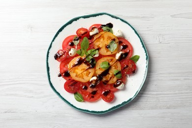 Photo of Tasty salad with balsamic vinegar and mozzarella on white wooden table, top view