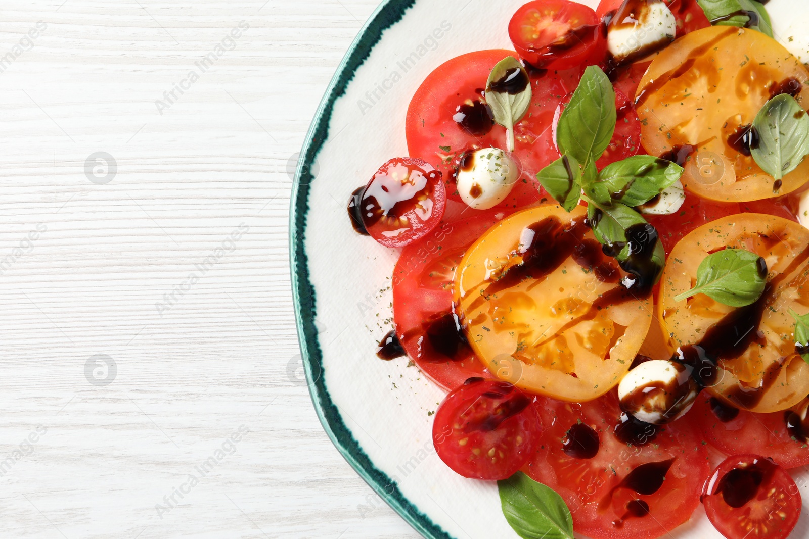 Photo of Tasty salad with balsamic vinegar and mozzarella on white wooden table, top view. Space for text