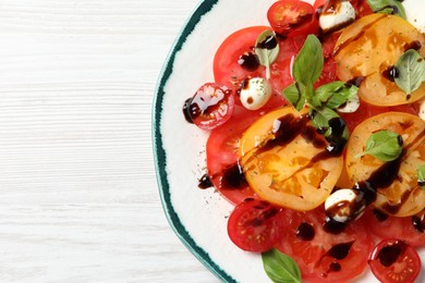 Tasty salad with balsamic vinegar and mozzarella on white wooden table, top view. Space for text