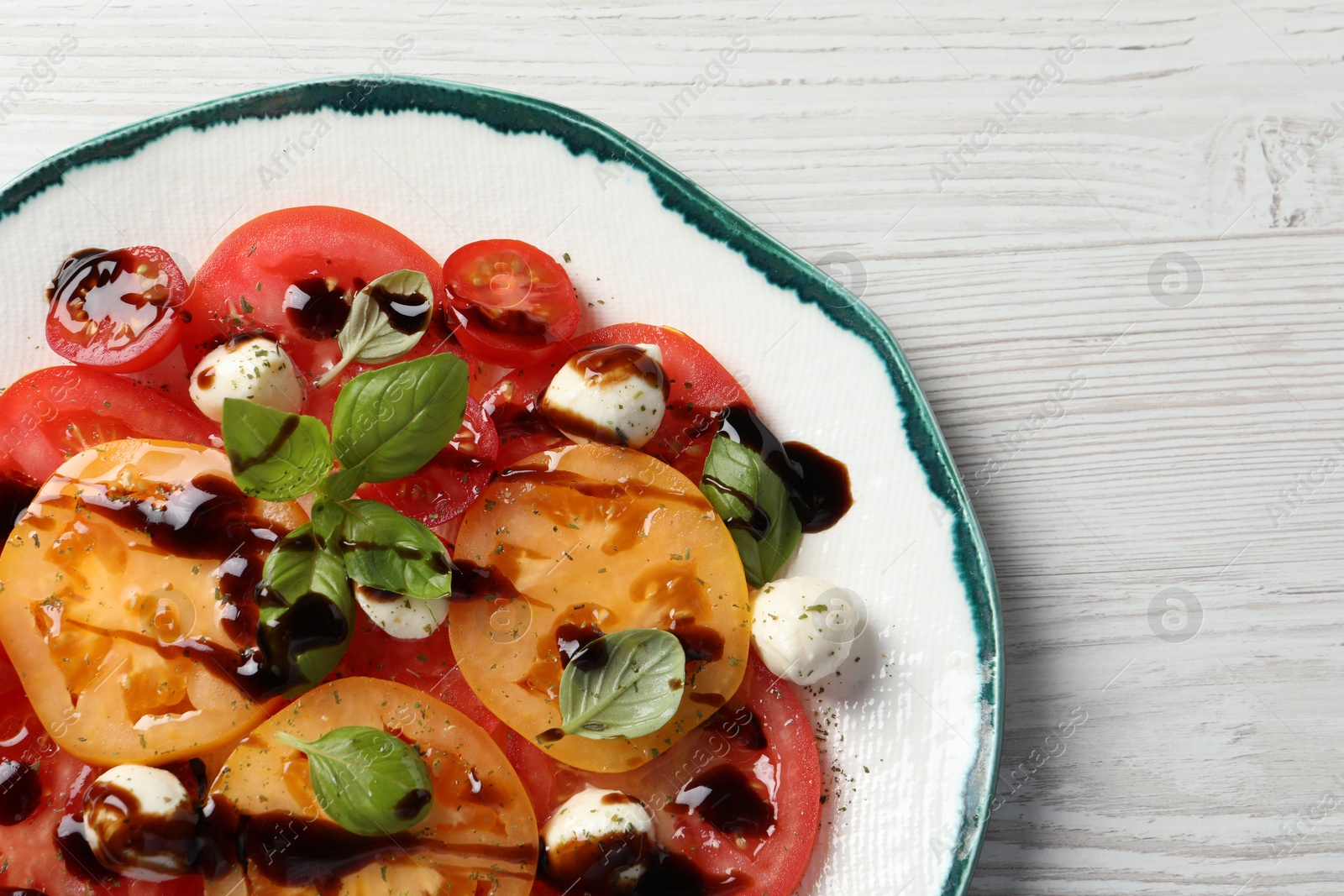 Photo of Tasty salad with balsamic vinegar and mozzarella on white wooden table, top view. Space for text