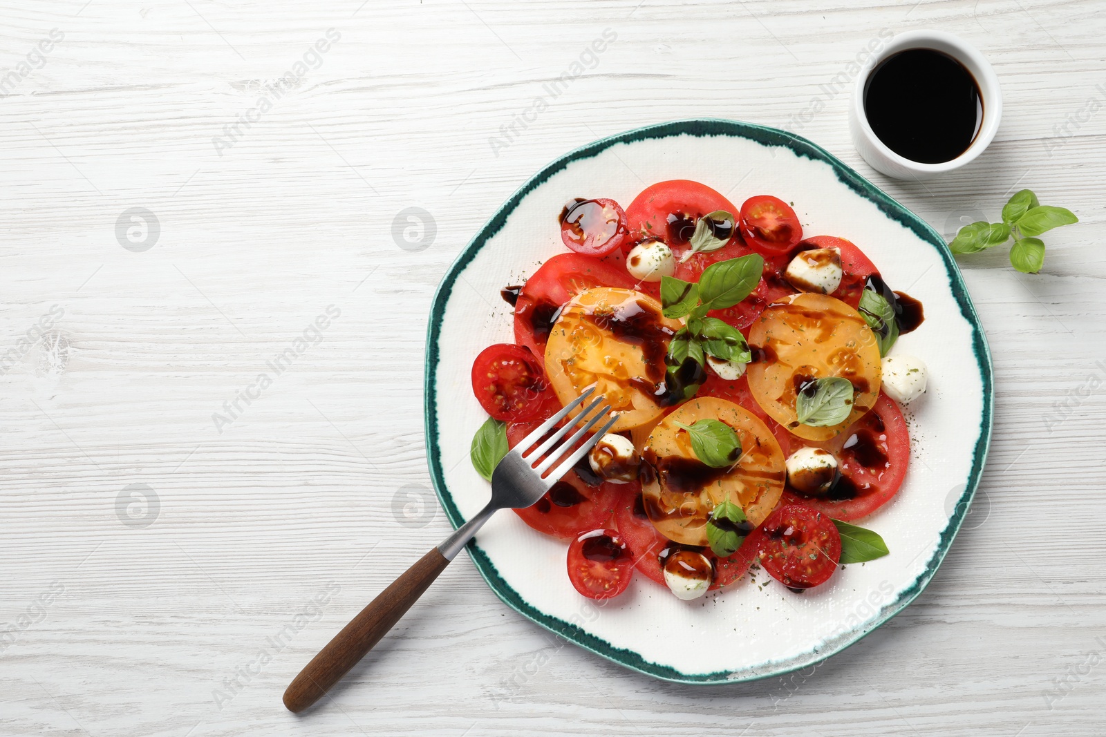 Photo of Tasty salad with balsamic vinegar and mozzarella on white wooden table, top view. Space for text